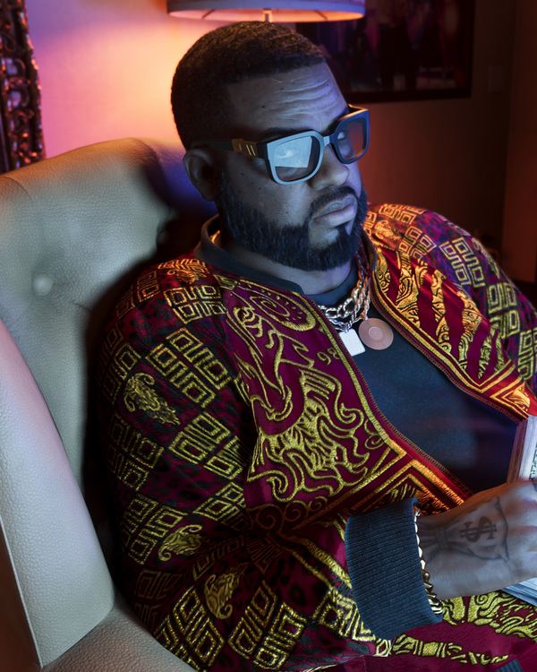 Boobie Ike in a patterned shirt, sitting back in an office chair
