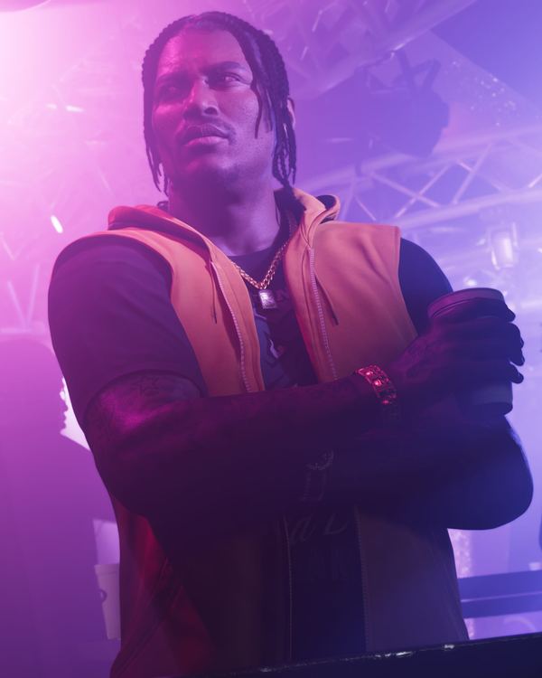 Dre'Quan Priest with his arms crossed in a purple-lit club